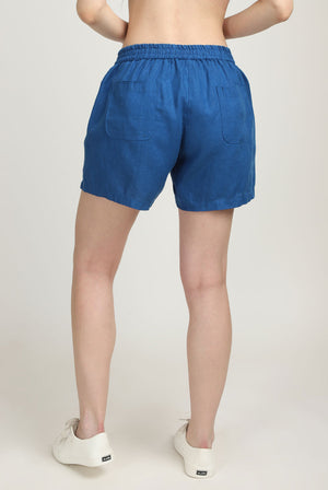 Girl in 100% linen blue shorts with pocket back view