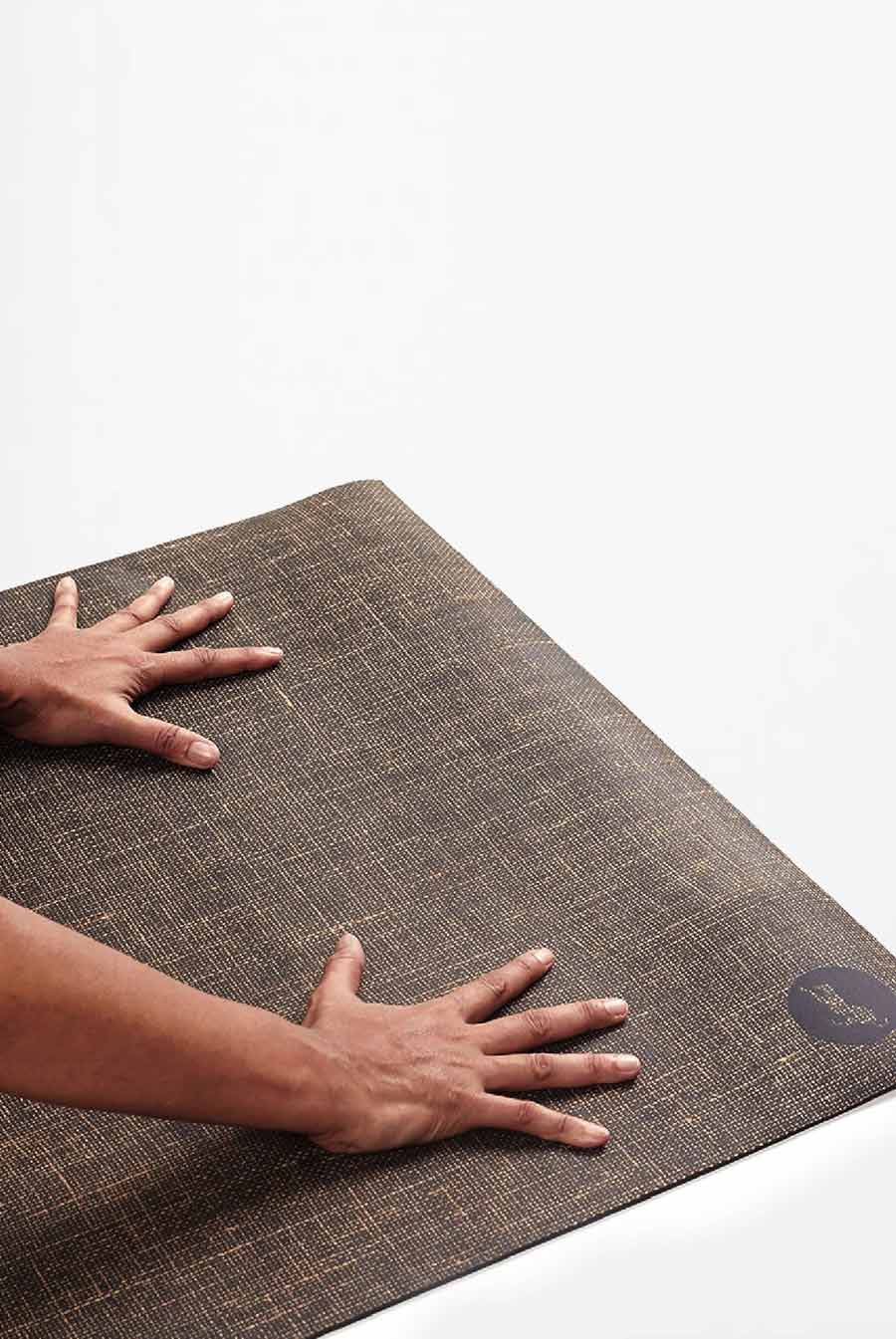 Hands testing grip on a natural rubber yoga mat, non-slip and sweat-resistant surface